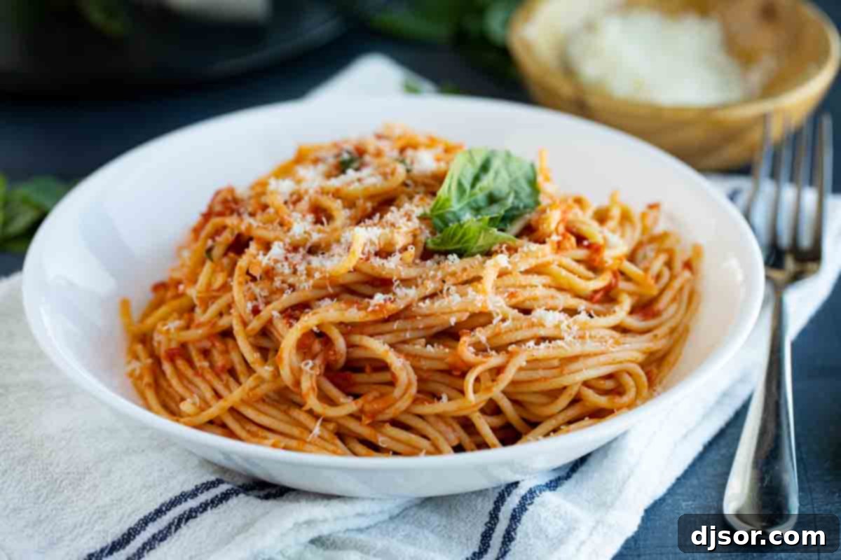 A bowl of fresh garlic spaghetti, generously topped with grated Parmesan cheese and vibrant basil leaves, ready to be served for a delicious weeknight meal.