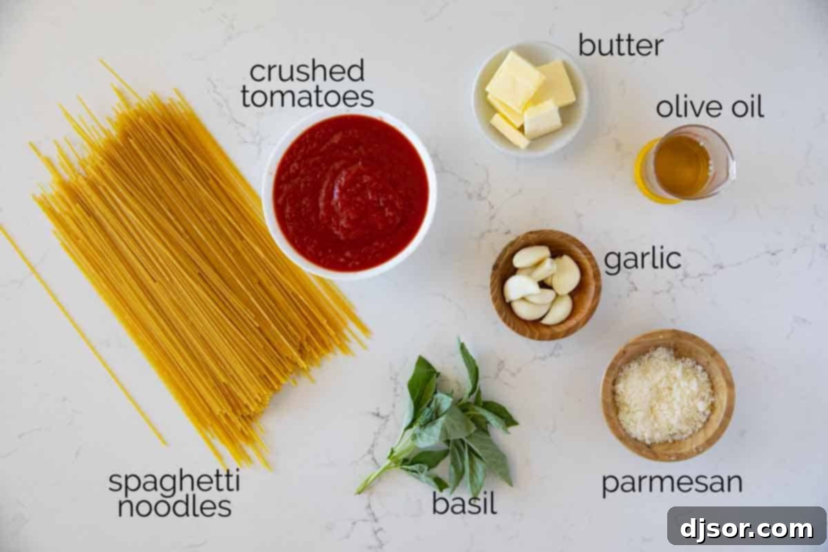 Fresh ingredients laid out for making garlic spaghetti, including whole garlic cloves, olive oil, tomatoes, basil, and spaghetti noodles.