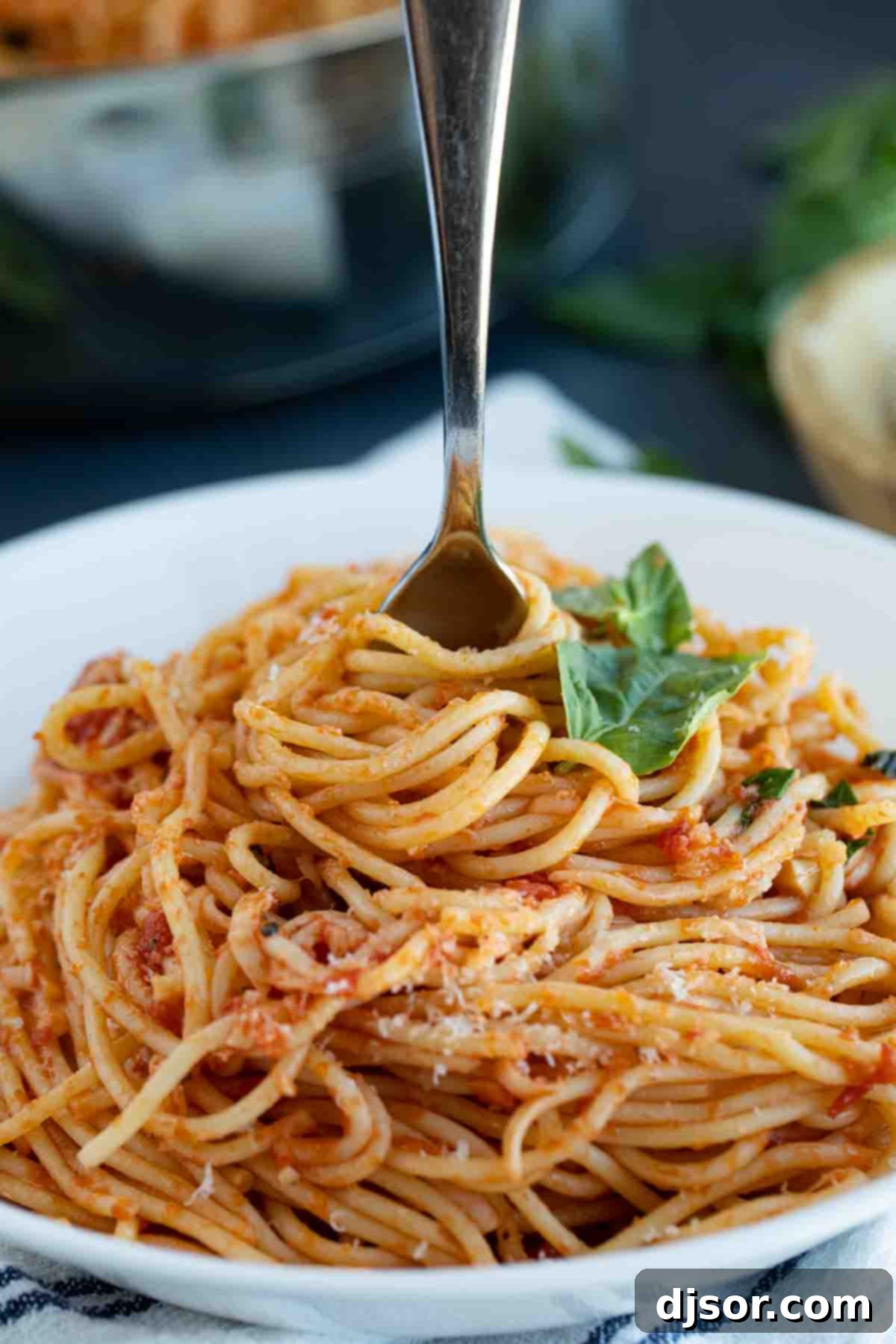 A close-up shot of a fork twirling a generous portion of garlic spaghetti, showcasing the rich sauce and perfectly cooked noodles.