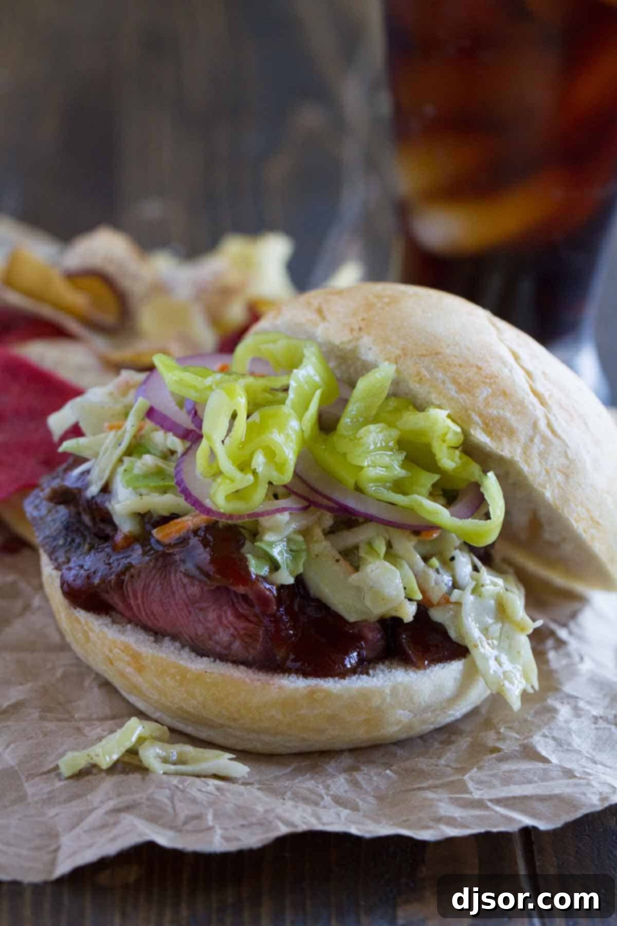 Flavorful Sliced Steak Sloppy Joes with Zesty Toppings A Sliced Steak Sloppy Joe with vibrant banana peppers and thinly sliced red onions as toppings, ready to be enjoyed.