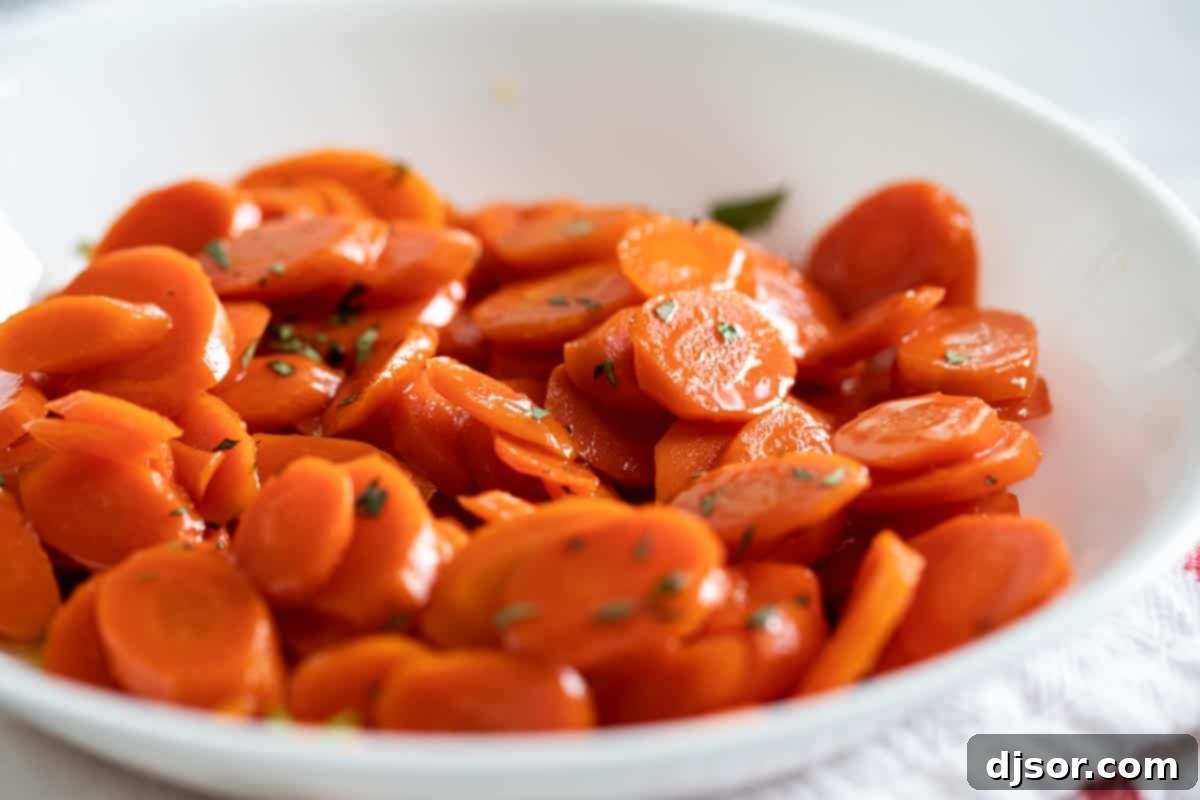 These Glazed Carrots are a simple side dish that add a bit of wow to your dinner. Cooked on the stovetop in a simple sugar and butter glaze, this carrot recipe will become a go-to! white bowl with glazed carrots