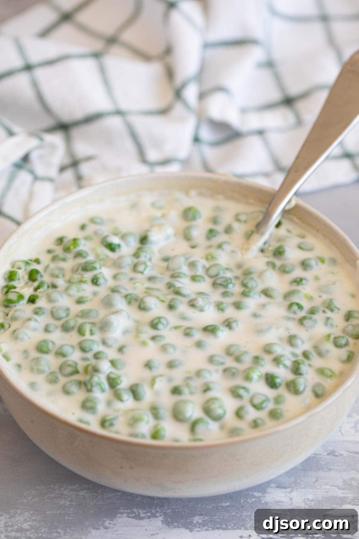 Bowl of creamed peas with a spoon.