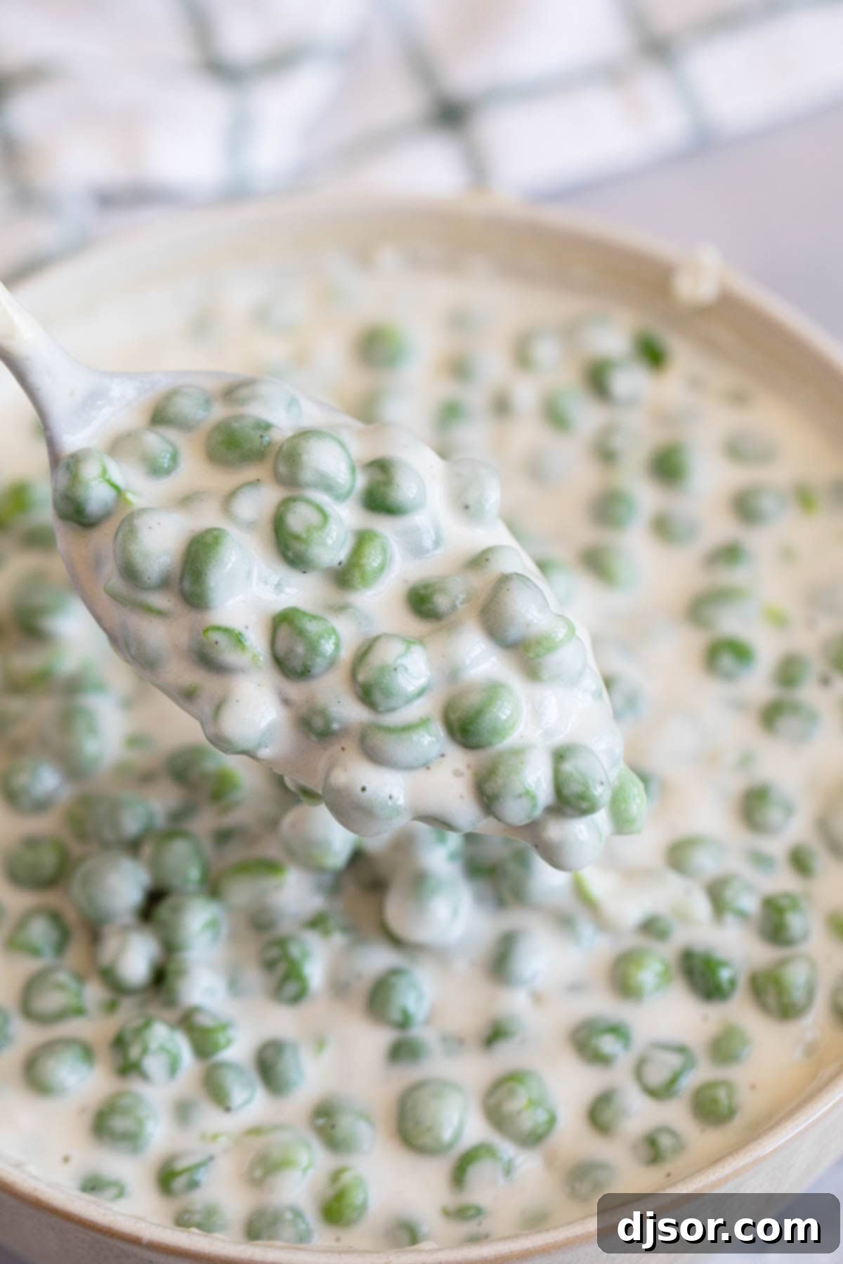 Spoonful of Creamed Peas over a bowl.